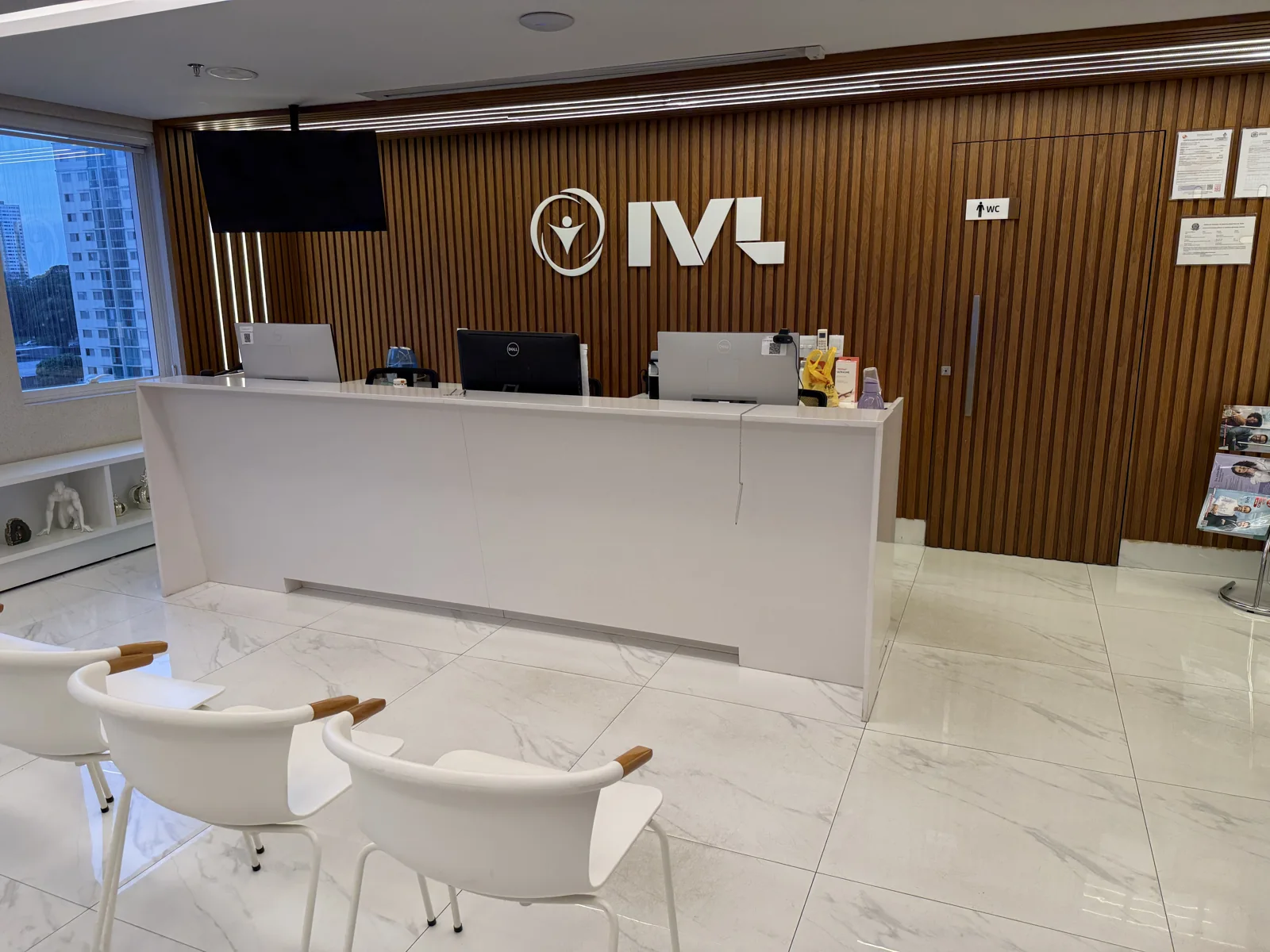 Recepção do IVL com balcão branco e identificação na parede de madeira